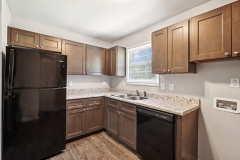 A kitchen with a black refrigerator and wooden cabinets.